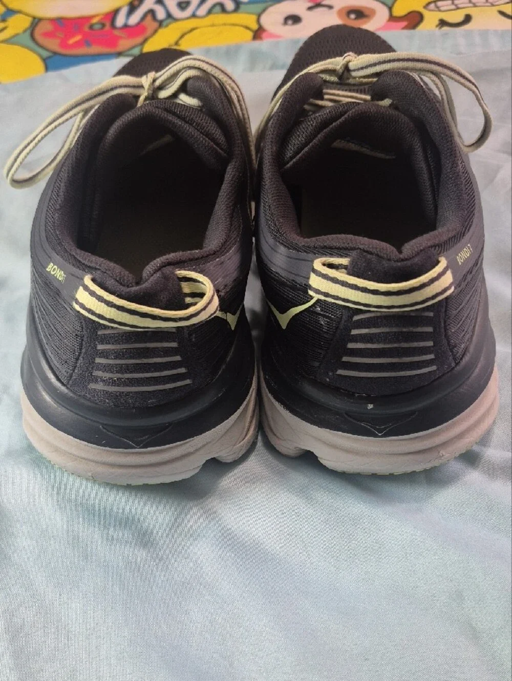 Hoka black running shoes with pale yellow logo